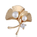 Elegante spilla a foglia di ginkgo dorata con perle bianche e zircone su sfondo bianco - Oro