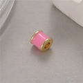 Detalle macro de una cuenta cilíndrica de esmalte rosa con bordes dorados para joyas DIY - Rosa