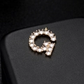Macro de colgante de letra G dorada con circonitas brillantes sobre fondo de cuero negro - Letra G Oro 14K (H-6581)