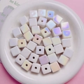 Macro shot of square iridescent beads with pearl luster on a white ceramic plate - White