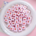 Nahaufnahme von rosa karierten quadratischen Perlen mit Kirschmuster für DIY-Schmuck - 14mm Würfel Lose Perle / Rosa Kirsche