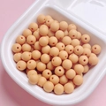 Detailed view of pale peach rubber-coated beads in a white grid tray for DIY jewelry - Khaki