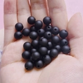 Macro shot of 8mm black matte rubber finish beads held in hand for DIY jewelry making - Black