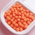 Macro detail of 6mm bright orange matte rubber-coated beads for DIY jewelry making - Orange