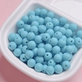 Macro view of sky blue rubber-coated matte beads in a white sorting tray for DIY jewelry - Peacock Blue