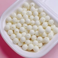 Close-up of matte white rubberized beads in a container for DIY jewelry and necklaces - Off White