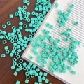 Macro view of mint green square acrylic beads with center holes on a wooden desk - Approx. 150 Pcs (5mm, 3mm Hole) / Cyan