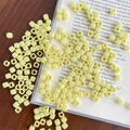 Close-up of cream yellow acrylic cube beads on a book for DIY jewelry making - Approx. 150 Pcs (5mm, 3mm Hole) / Light Yellow