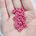 Macro detail of small pink wave-shaped alloy spacer beads with glossy glazed texture - 6.3mm / Rose Pink