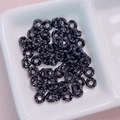 Close-up of black flower-shaped spacers with white polka dots for DIY jewelry making - 6.3mm / Black