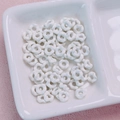 Close-up of white wave-edge flower beads in a ceramic bowl for DIY jewelry making - 6.3mm / White
