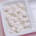 Vista macro de cuentas de acrílico blanco con forma de caramelo para joyería DIY - 11x17mm / Crema