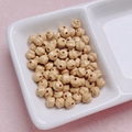 Macro detail of nude faceted acrylic beads with threading holes in a white ceramic tray - 6mm / Brown