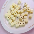 Close-up of 12mm macaron yellow acrylic square beads with center holes on a ceramic plate - 12mm / Light Yellow