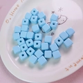 Macro shot of 12mm light blue acrylic cube beads in a white ceramic decorative plate - 12mm / Light Blue