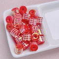Macro view of red cylindrical striped barrel beads with gold metallic grid for DIY jewelry - Red