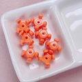 Detail of orange cross-shaped acrylic beads with glossy finish and center holes for DIY - 10x15mm / Orange