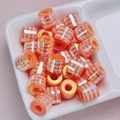 Detailed macro view of orange gingham checkered cylindrical beads with an iridescent UV finish - Orange