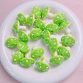 Detailed view of green mushroom acrylic beads with white dots in a white ceramic dish - Green