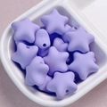 Dettaglio macro di perle a stella in acrilico lavanda opaco con fori passanti su un piatto - Viola