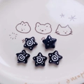Macro shot of five black star-shaped acrylic beads with white swirl and polka dot patterns - Black