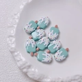 Detailopname van tien blauw-witte ijslolly kralen op een wit keramisch bloemenbordje - Per stuk verkocht (20x12mm) / Cyaan
