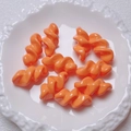 Polished orange acrylic spiral beads for DIY jewelry displayed on a white ceramic tray - 27.5x14mm / Orange
