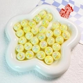Dettaglio di perle rotonde crema luminose con finitura iridescente in un piatto a fiore - 16mm / Giallo Luminoso