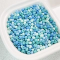 Macro detail of 4mm high-quality blue and green Czech glass seed beads in a white tray - (Sold by Pack/Approx 200 Pcs) Diameter 4mm Hole 1.2mm / 05