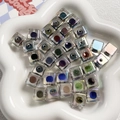 Vista macro di perle a cubo iridescenti con nuclei colorati e rivestimento AB nel vassoio - Perline quadrate