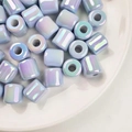 Gros plan de perles cylindriques en acrylique irisées dans un bol en céramique blanche - Diamètre env. 16mm Trou env. 6mm / Bleu Irisé