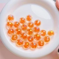 Close-up of 16mm transparent orange aurora beads for DIY jewelry making in a white ceramic dish - Diameter about 16mm Aperture about 2.5mm / Orange