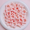 Primo piano di perline acriliche iridescenti a forma di stella cava in una ciotola - Rosa