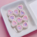Close-up of pink iridescent heart bow beads with faceted texture in a ceramic tray - Pink