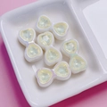 Macro detail of heart bow charms with yellow crystals for DIY jewelry making - Yellow