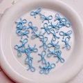 Macro shot of light blue bow-shaped alloy beads for DIY jewelry and phone chain charms - Blue