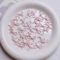 Close-up of pink alloy bow beads for DIY jewelry making on white ceramic plate - Light Pink