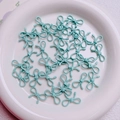 Macro shot of mint green alloy bow beads for DIY jewelry and phone charms - Cyan