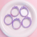 Macro shot of five iridescent lavender rings with bow accents on a white plate - Purple