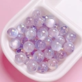 Macro shot of iridescent lavender acrylic beads with central drill holes for DIY jewelry - Purple