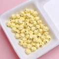 Detalle de cuentas de estrella en esmalte amarillo de 7mm para joyería DIY en un plato blanco - 7mm / Amarillo