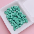 Makroaufnahme von 7mm minzgrünen Emaille Sternfruchtperlen in weißer Schale für DIY - 7mm / Cyan