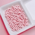 Macro shot of colorful light pink donut-shaped alloy beads for DIY jewelry making - Pink