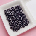 Close-up of glossy black donut beads for DIY jewelry making in a ceramic dish - Black