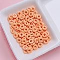 Macro detail of glossy orange donut-shaped alloy beads for DIY jewelry making - Orange