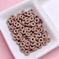 Macro shot of glossy chocolate brown donut-shaped beads in a white sorting tray - Brown