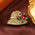 Dettaglio ravvicinato di una spilla vintage a forma di cappello con fiori di strass - Oro Antico-Champagne