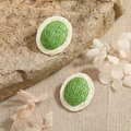 Detail view of handmade woven oval earrings in green and white on natural linen - Grass Green And Off-White