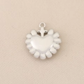 Macro shot of silver heart pendant with petal edges and a small cross connector charm - Silver