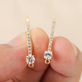 Detailed close-up of 18k gold plated U-shaped earrings with micro-pave crystals and ring loops - Gold